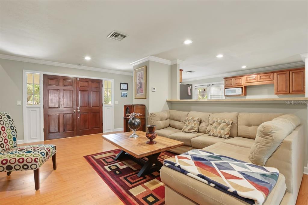 A living room with wood floors, a sectional sofa, and a wooden front door — 200 CROOKED OAK COURT, LONGWOOD, FL