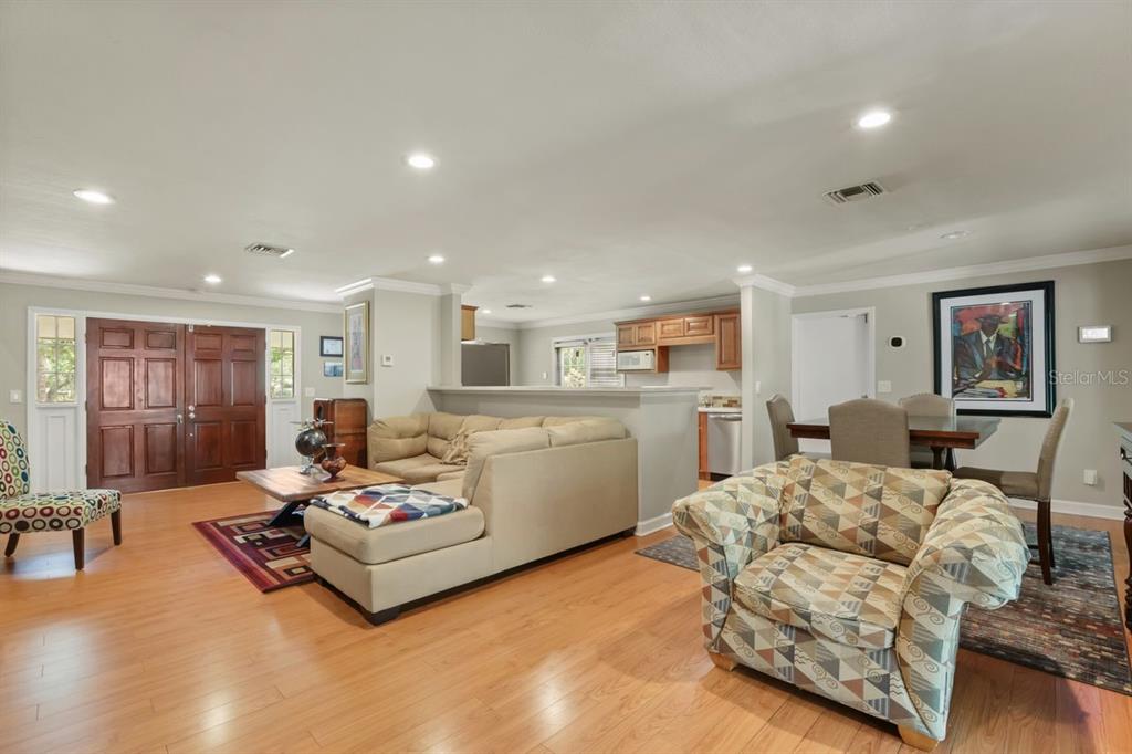 An open-concept living and dining area features hardwood floors, a sectional sofa, and recessed lighting — 200 CROOKED OAK COURT, LONGWOOD, FL