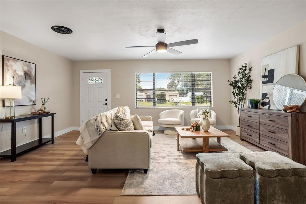 A living room features a sofa, coffee table, two ottomans, and a dresser on wood floors — 1348 RADCLYFFE ROAD, ORLANDO, FL