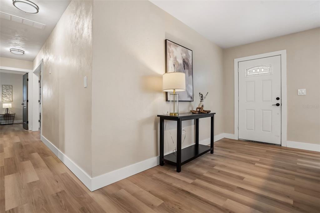 An entryway features light wood-look flooring, a black console table with a lamp, and a door — 1348 RADCLYFFE ROAD, ORLANDO, FL
