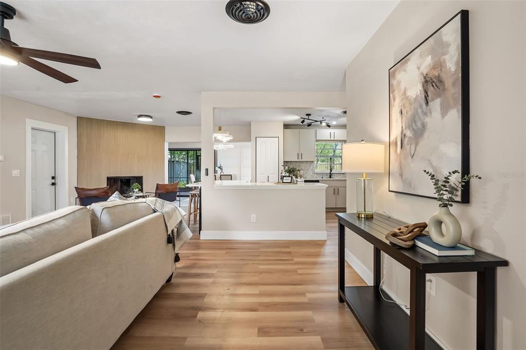 A living room with light wood floors leads to an open kitchen with white cabinets — 1348 RADCLYFFE ROAD, ORLANDO, FL