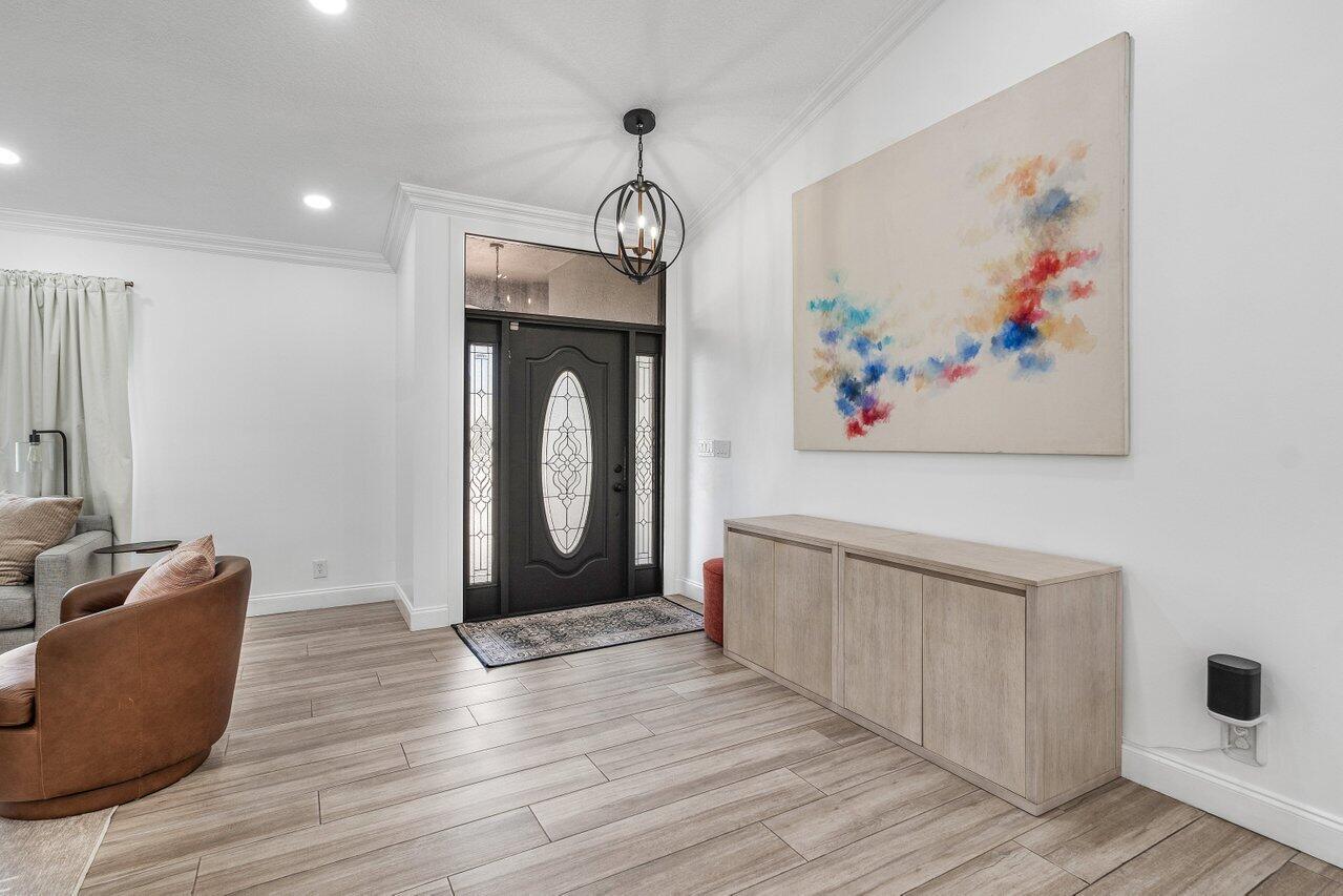 An entryway features a dark front door, light wood-look flooring, and a large abstract painting — 990 NW 8th Street, Boca Raton FL 33486, BOCA RATON, FL