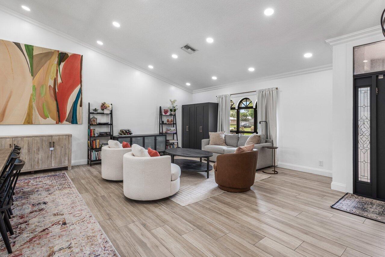 A living room features light wood-look flooring, recessed lighting, white walls, and modern furniture — 990 NW 8th Street, Boca Raton FL 33486, BOCA RATON, FL