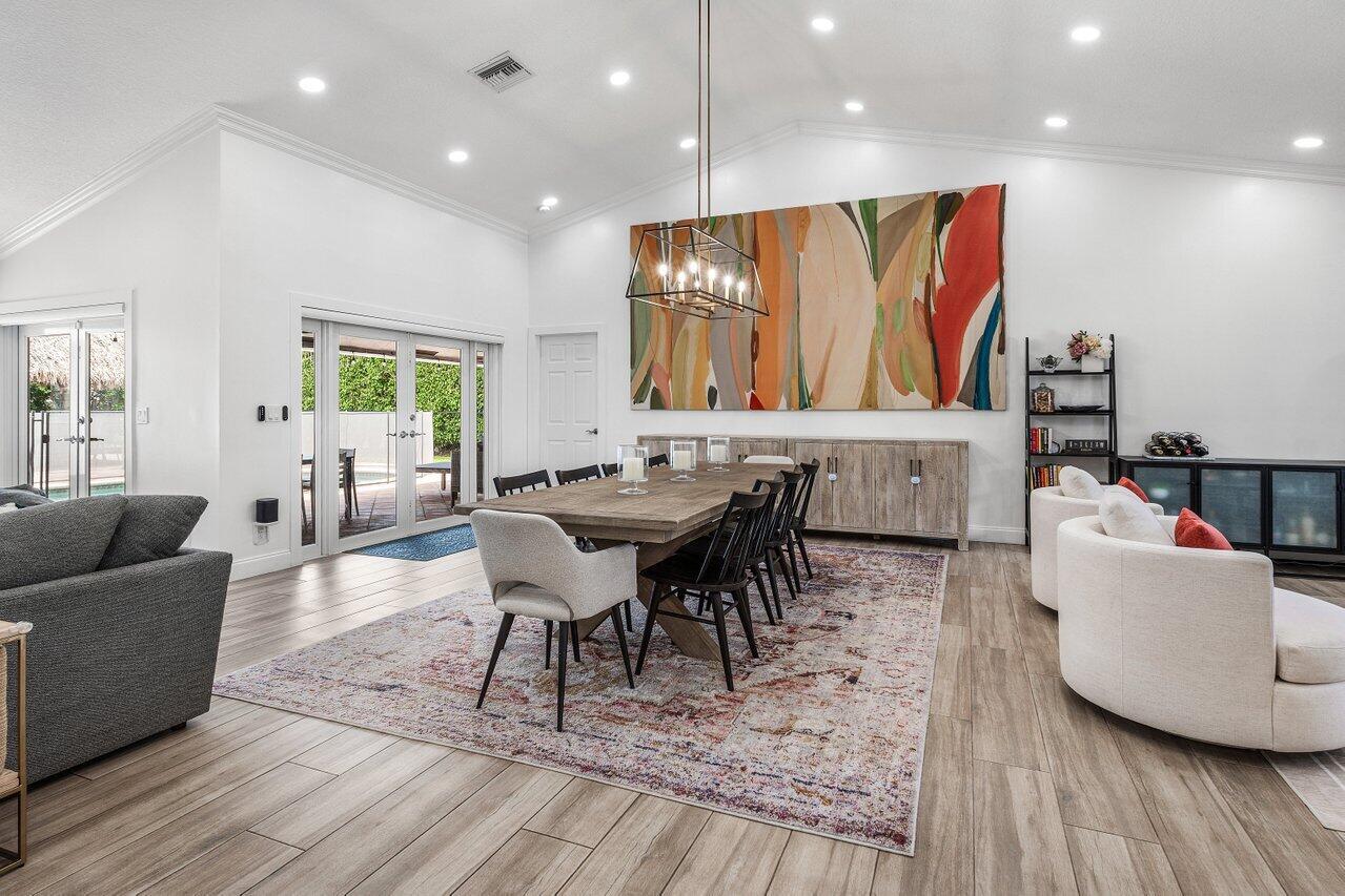 A dining room features a wooden table, a large abstract painting, and light wood flooring — 990 NW 8th Street, Boca Raton FL 33486, BOCA RATON, FL