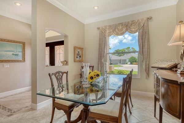 A dining room features a glass-topped table, wooden chairs, tile flooring, and a large window — 9477 CEDAR RIDGE LANE, SARASOTA, FL