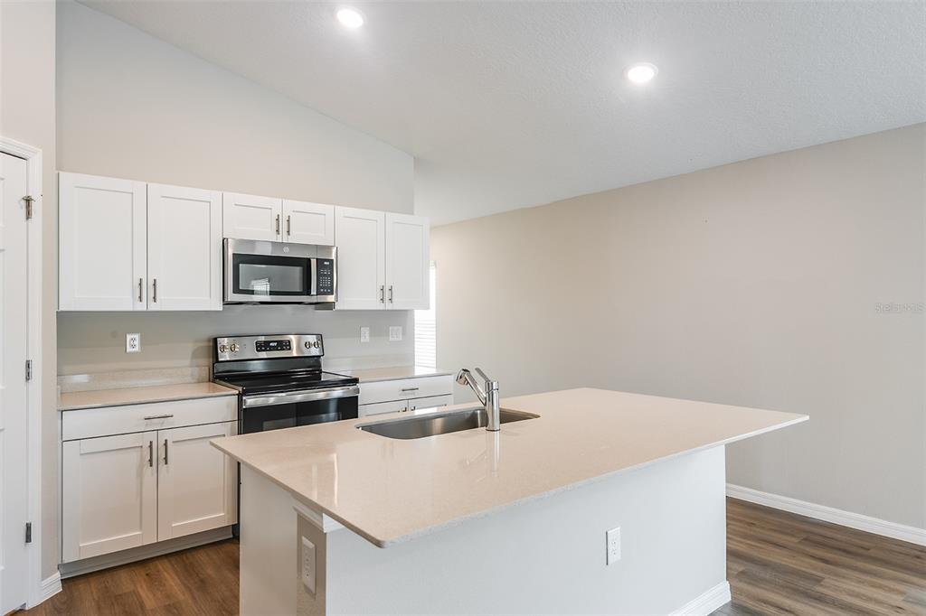 A kitchen with white cabinets, stainless steel appliances, and a central island with a sink — 5393 SAN PIETRO DRIVE, WINTER HAVEN, FL