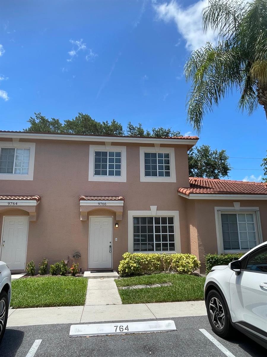 A two-story tan stucco townhouse with a tiled roof and a small front walkway — 9766 Kamena Circle, Boynton Beach FL 33436, BOYNTON BEACH, FL