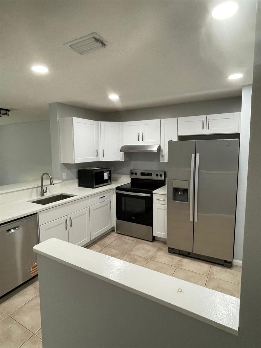 A kitchen features white cabinets, stainless steel appliances, and light-colored countertops — 9766 Kamena Circle, Boynton Beach FL 33436, BOYNTON BEACH, FL