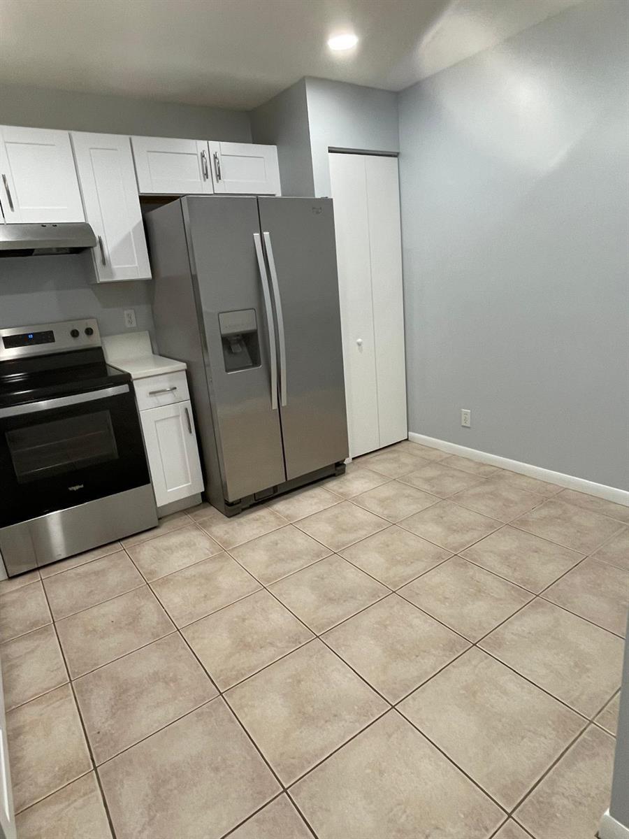 A kitchen features white cabinets, stainless steel appliances, and light-colored tile flooring — 9766 Kamena Circle, Boynton Beach FL 33436, BOYNTON BEACH, FL