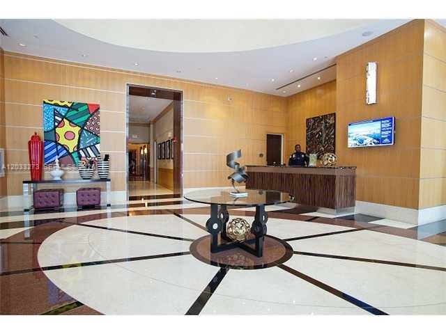 A modern lobby features a circular table, a reception desk, and colorful abstract wall art — 253 NE 2nd St # 509, Miami FL 33132, MIAMI, FL