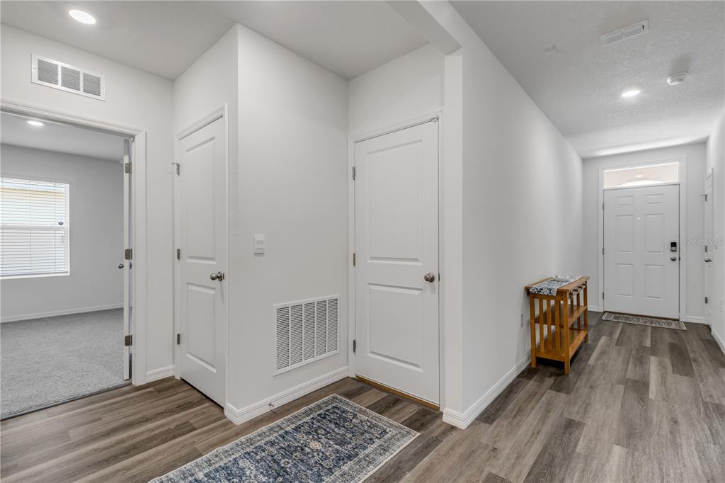 An interior hallway features wood-look flooring, white walls, two closed doors, and a front entrance — 507 CORONADO COVE ROAD, NEW SMYRNA BEACH, FL
