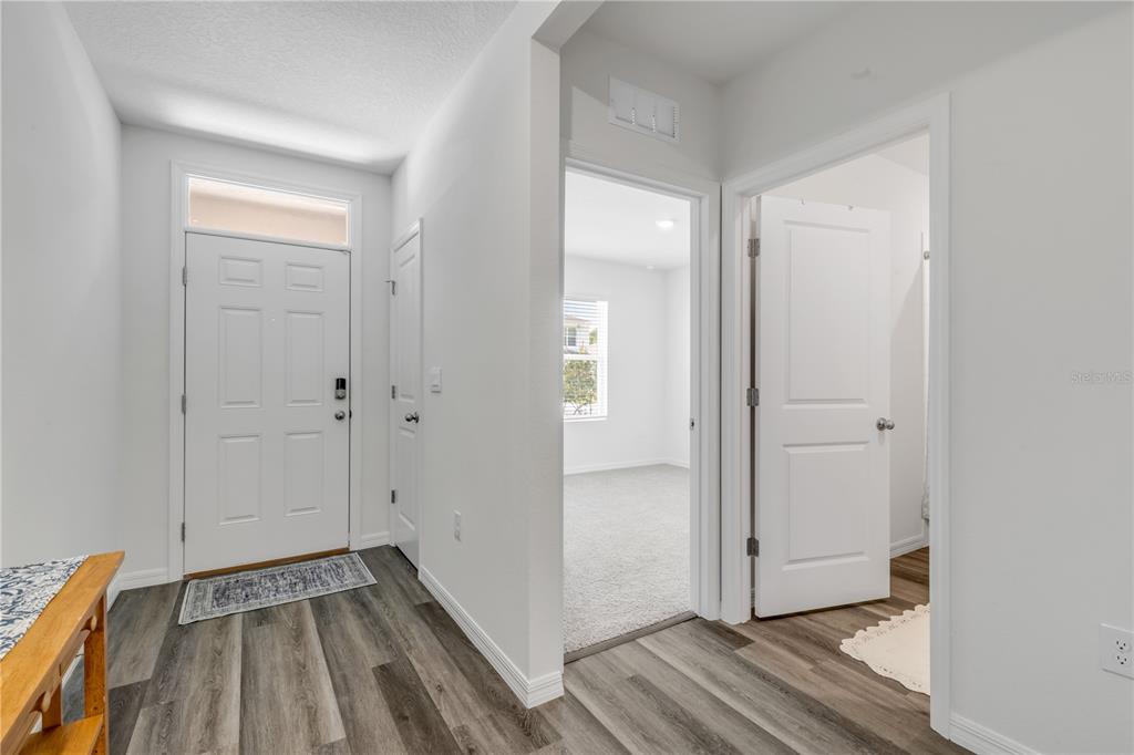 A bright entryway features wood-look flooring, a white front door, and two interior doorways — 507 CORONADO COVE ROAD, NEW SMYRNA BEACH, FL