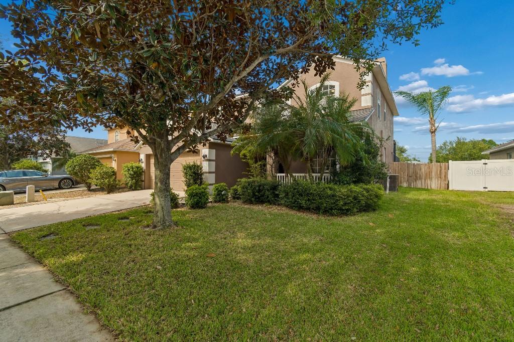 A two-story house with a tan exterior, a front lawn, and a paved driveway — 12215 ADVENTURE DRIVE, RIVERVIEW, FL