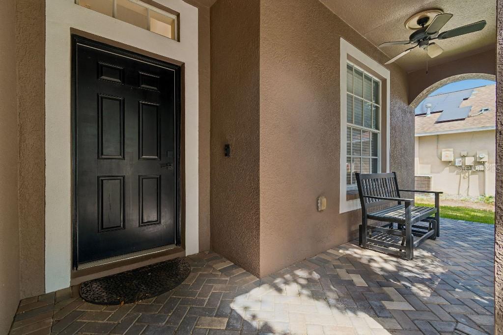 A covered front porch with a black door, a wooden bench, and a ceiling fan — 12215 ADVENTURE DRIVE, RIVERVIEW, FL