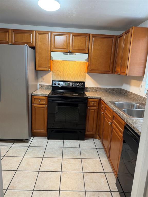 A kitchen features wood cabinets, a black stove, a stainless steel refrigerator, and tiled flooring — 8237 RAVENCROFT DRIVE, TAMPA, FL