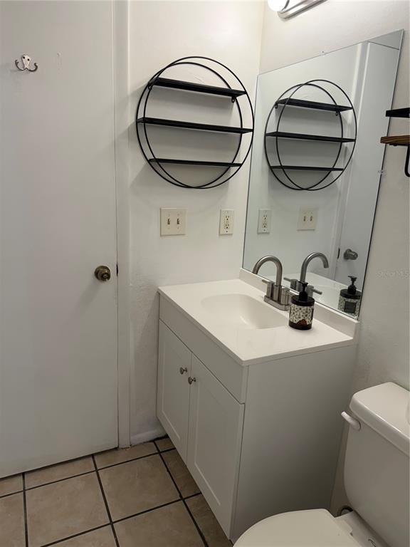 A bathroom features a white vanity with a sink, a round wall shelf, and a mirror — 8237 RAVENCROFT DRIVE, TAMPA, FL