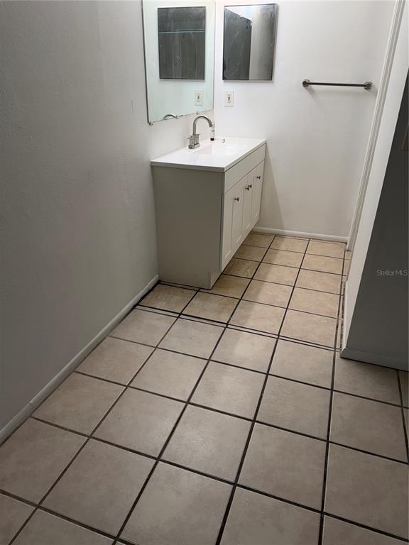 A bathroom features a white vanity with a sink, a mirror, and tiled flooring — 8237 RAVENCROFT DRIVE, TAMPA, FL