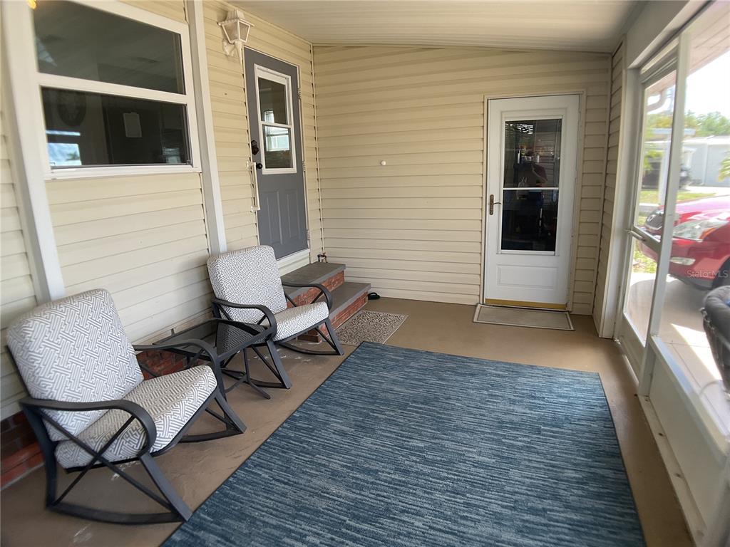 A covered porch features two rocking chairs, a blue area rug, and two exterior doors — 2100 KINGS HIGHWAY UNIT 577, PUNTA GORDA, FL