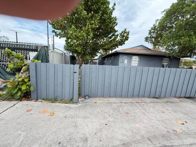 A gray wooden fence stands in front of a single-story house with a brown roof — 714 S H Street, FL 33460, FL