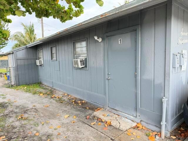 A gray, single-story building with a door labeled number one and two window air conditioners — 714 S H Street, FL 33460, FL