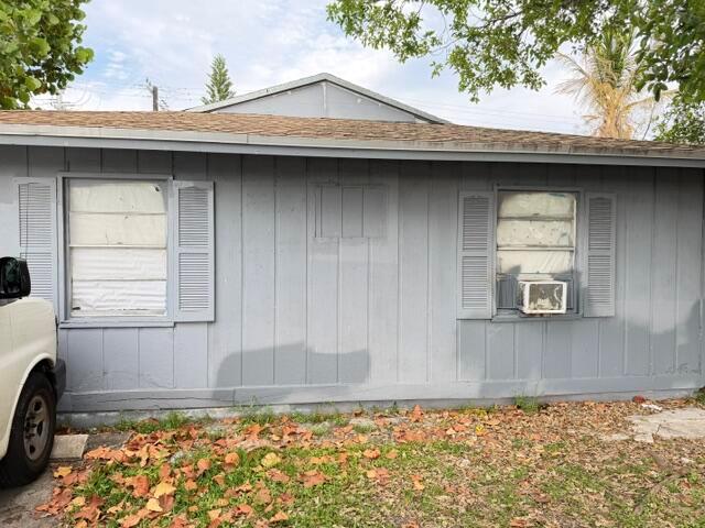 The exterior of a single-story house features gray vertical siding, two windows with shutters, and an air conditioner — 714 S H Street, FL 33460, FL