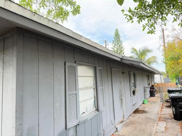 A side view of a gray house exterior featuring vertical siding, shutters, and a window — 714 S H Street, FL 33460, FL