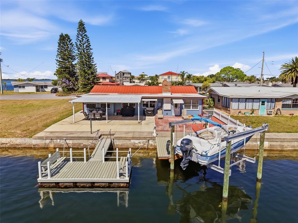 A waterfront house with a red metal roof, a boat lift, and a private dock — 13520 ALLYN DRIVE, HUDSON, FL