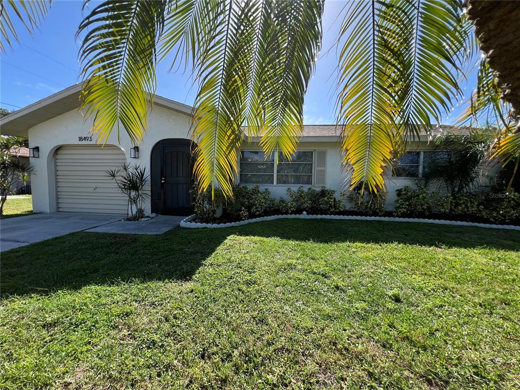A single-story house with a white exterior, a garage, and palm fronds in the foreground — 18493 LAKE WORTH BOULEVARD, PORT CHARLOTTE, FL