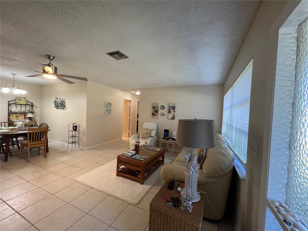 A living room and dining area with tile floors, a ceiling fan, and beige furniture — 18493 LAKE WORTH BOULEVARD, PORT CHARLOTTE, FL