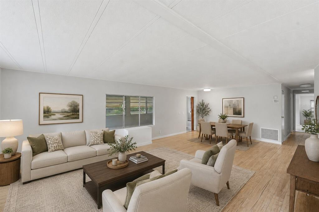 A bright living and dining area with light wood flooring, neutral walls, and modern furniture — 4128 WOODLAND CIRCLE, DELAND, FL