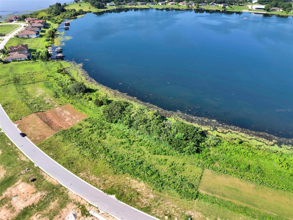 An aerial view shows a residential street bordering a large lake and undeveloped land — 4283 JULIANA LAKE DRIVE, AUBURNDALE, FL