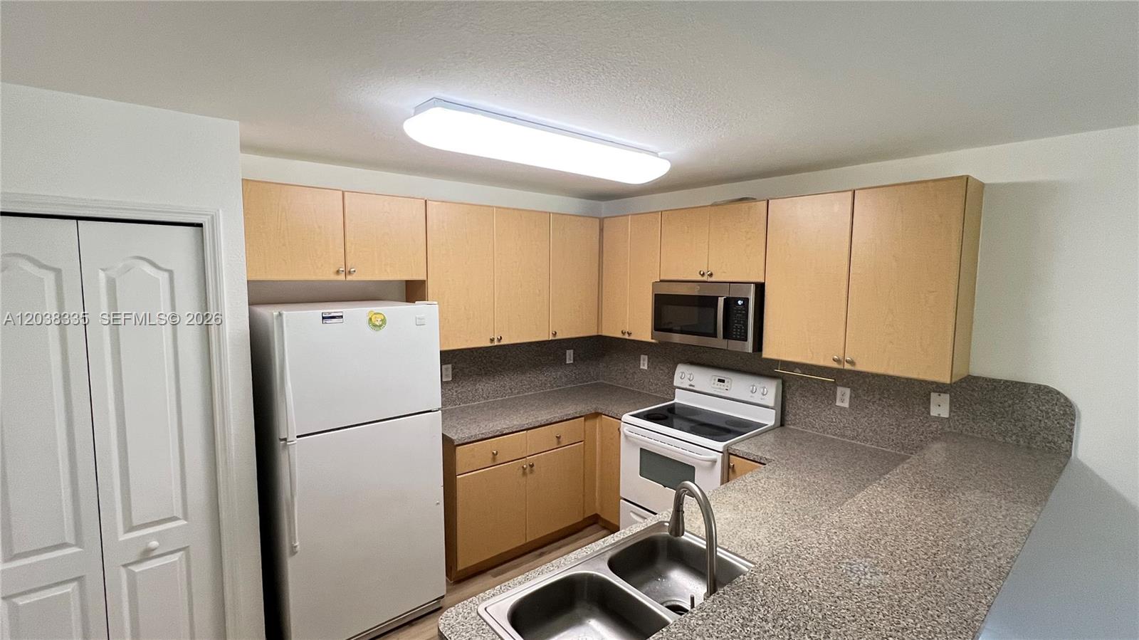 A kitchen features light wood cabinets, speckled laminate countertops, and white appliances — 22721 SW 88th Pl # 19, Cutler Bay FL 33190, CUTLER BAY, FL