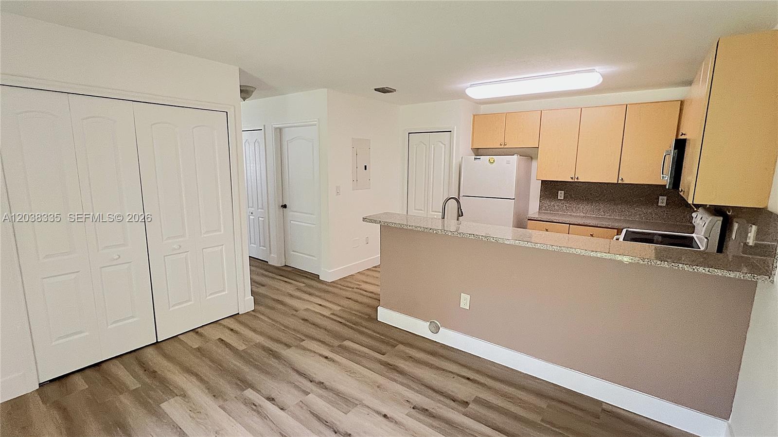 A kitchen with light wood cabinets and a granite breakfast bar overlooks a living area — 22721 SW 88th Pl # 19, Cutler Bay FL 33190, CUTLER BAY, FL