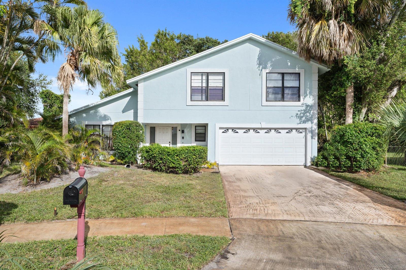 A light blue two-story house with a white garage door and a concrete driveway — 5900 Flatrock Road, West Palm Beach FL 33413, WEST PALM BEACH, FL