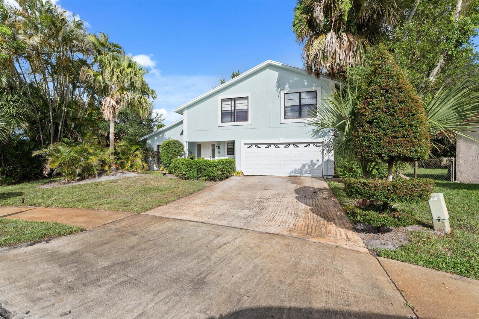A light blue two-story house features a white garage door and a concrete driveway — 5900 Flatrock Road, West Palm Beach FL 33413, WEST PALM BEACH, FL