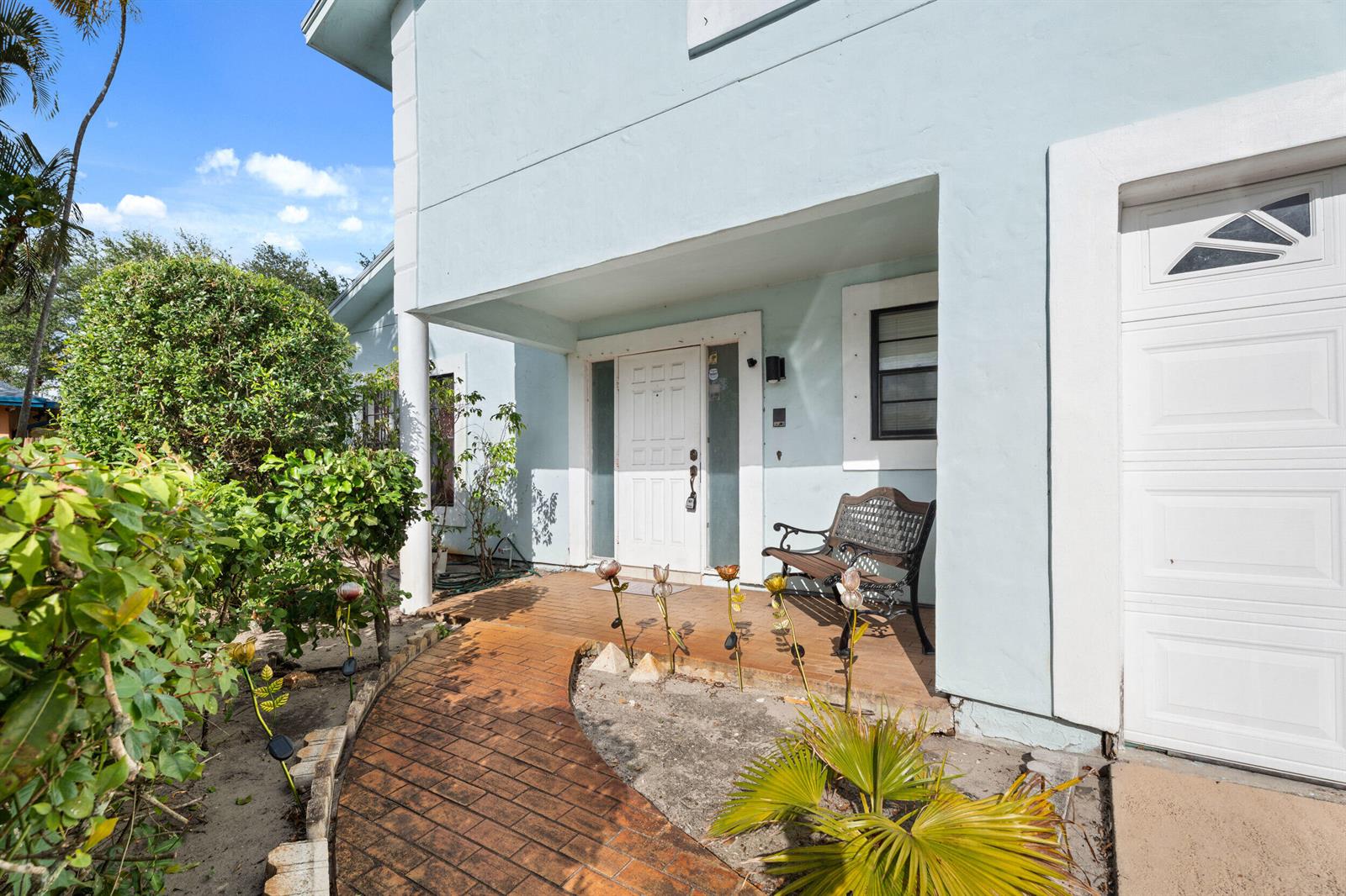 The exterior of a light blue house features a brick walkway, front porch, and garage — 5900 Flatrock Road, West Palm Beach FL 33413, WEST PALM BEACH, FL