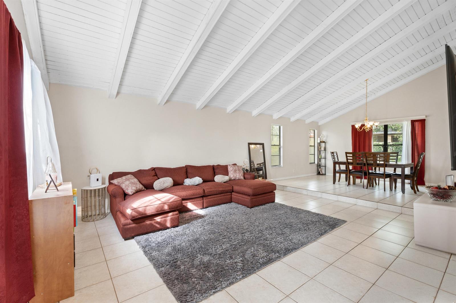A living and dining room with vaulted ceilings, tile floors, and a large red sectional — 5900 Flatrock Road, West Palm Beach FL 33413, WEST PALM BEACH, FL