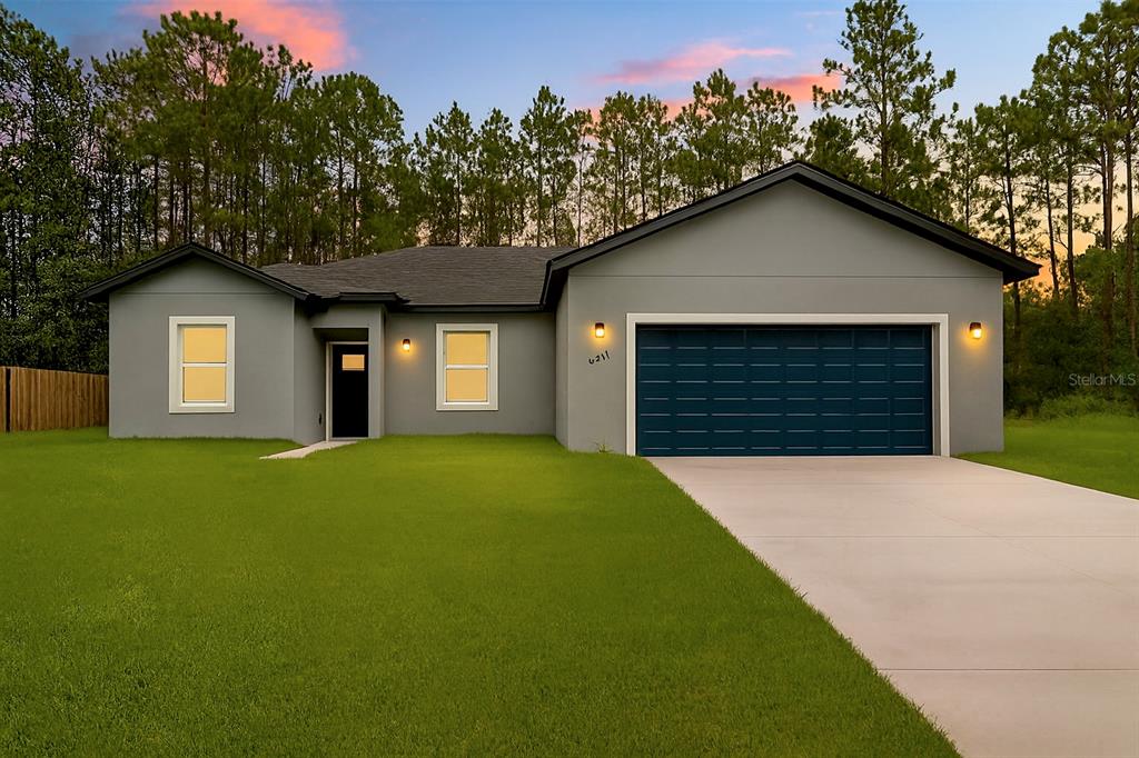 The back exterior of a single-story gray house features a covered patio and lawn — 6211 SW 144TH STREET RD, OCALA, FL