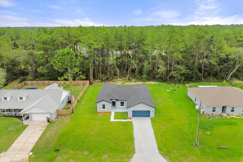 An aerial view shows a house with a dark shingled roof and a concrete driveway — 6211 SW 144TH STREET RD, OCALA, FL