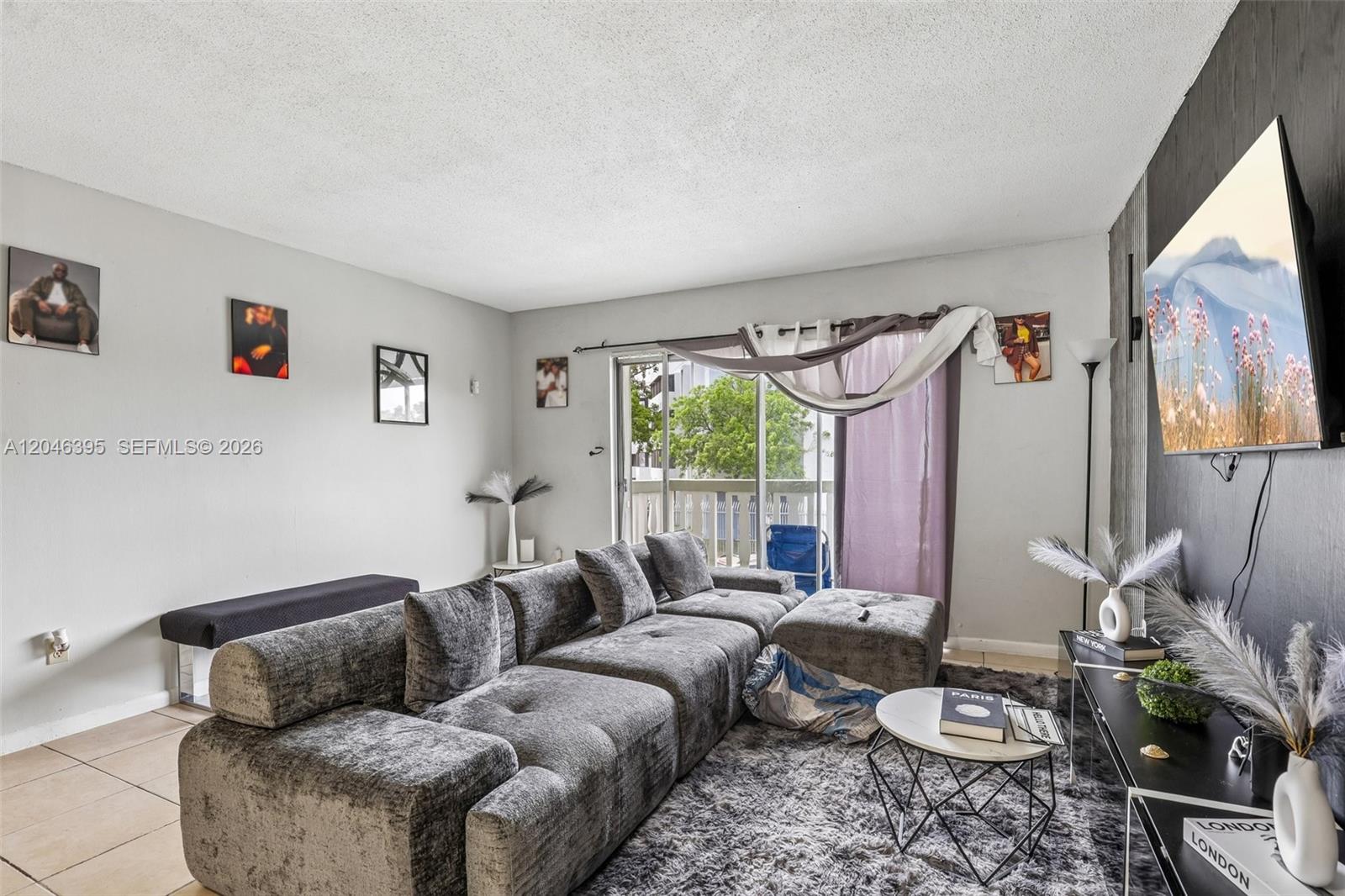 A living room features a large gray sectional sofa, a shag rug, and a wall-mounted television — 15225 NE 6th Ave # B208, Miami FL 33162, MIAMI, FL