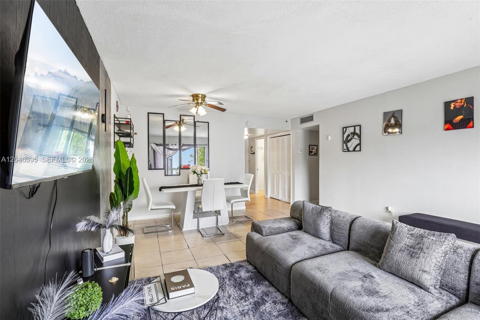 A living room and dining area feature a gray sectional sofa, tile floors, and mirrors — 15225 NE 6th Ave # B208, Miami FL 33162, MIAMI, FL