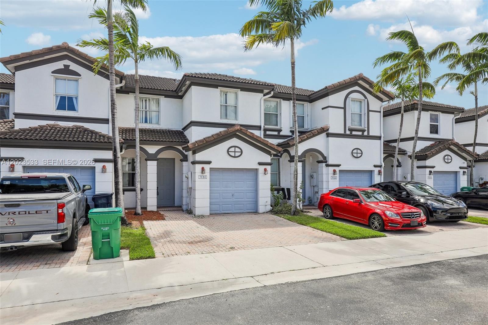 A row of two-story townhouses features white stucco exteriors, tiled roofs, and paved driveways — 7616 NW 114th Path # 7616, Doral FL 33178, DORAL, FL