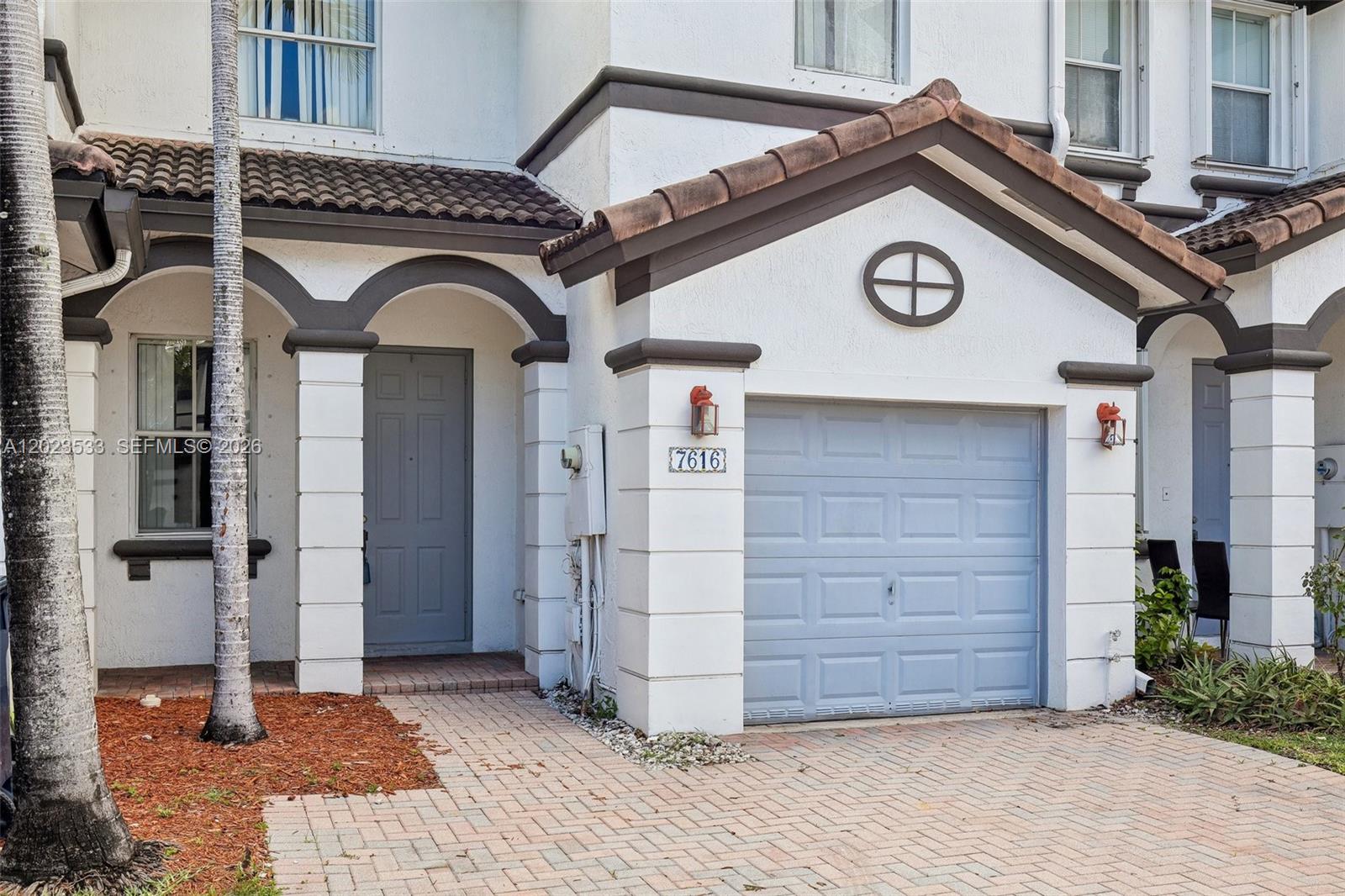 The exterior of a two-story townhouse features a garage, a front door, and a paved driveway — 7616 NW 114th Path # 7616, Doral FL 33178, DORAL, FL