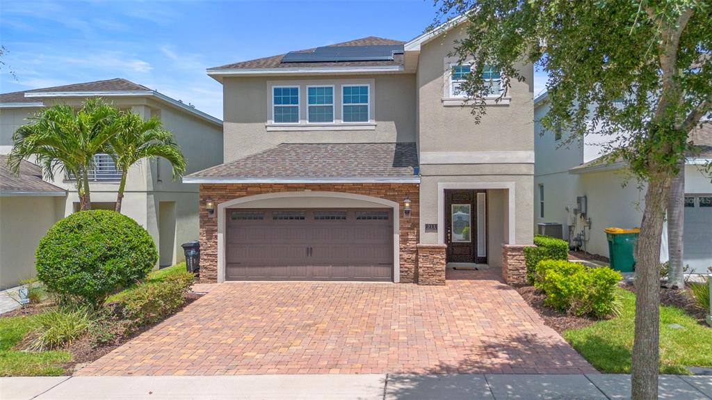 A two-story house with a stone-accented garage, brick paver driveway, and a front entrance — 311 PENDANT COURT, KISSIMMEE, FL