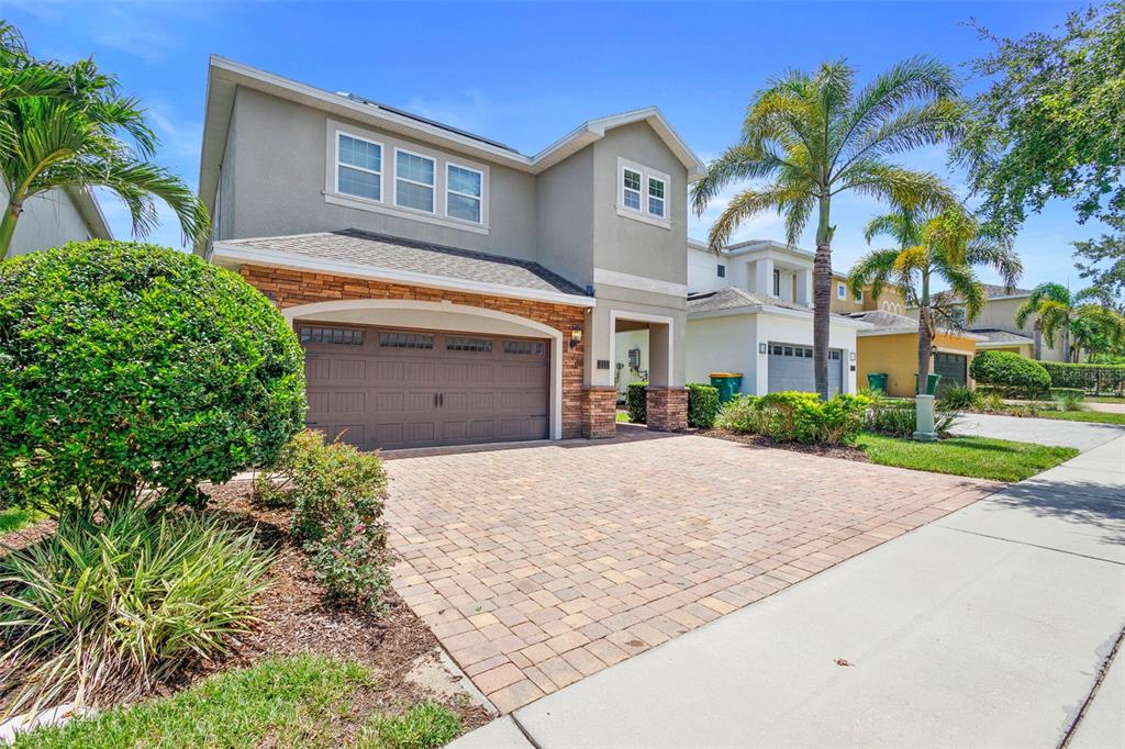 A two-story house with a stone-accented facade, a paved driveway, and a two-car garage — 311 PENDANT COURT, KISSIMMEE, FL