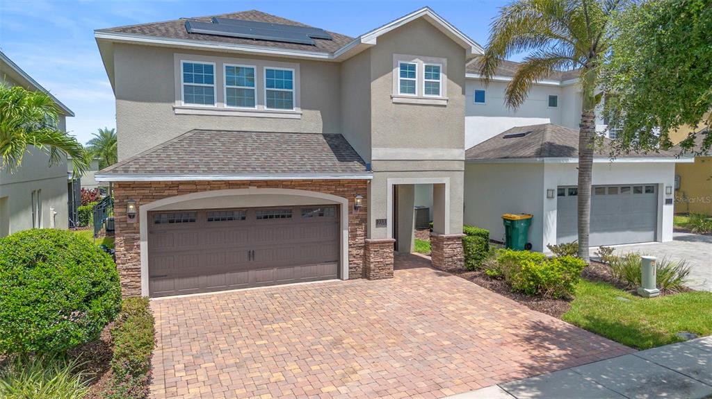 A two-story suburban house with a stone-accented garage and a paved driveway — 311 PENDANT COURT, KISSIMMEE, FL