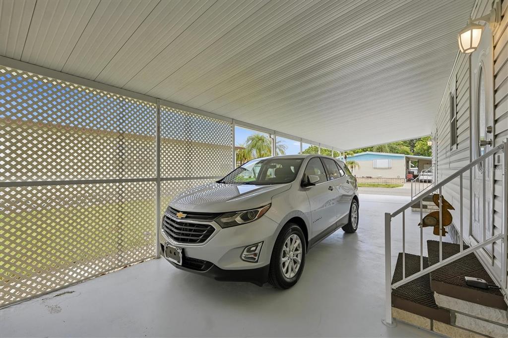 A silver SUV is parked under a covered carport next to a home with stairs — 808 53RD AVENUE E UNIT 88, BRADENTON, FL