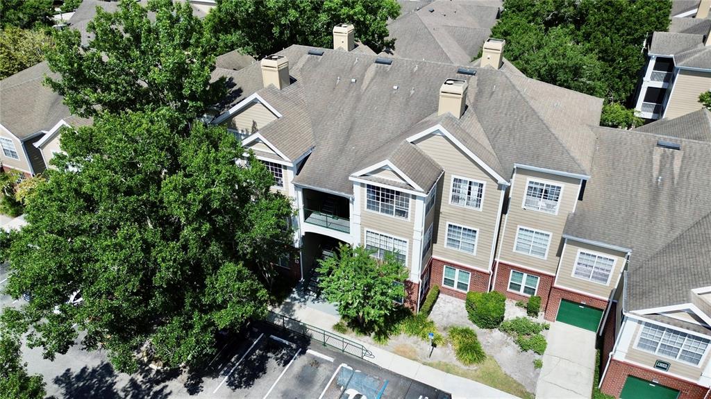 An aerial view shows a multi-story apartment building with tan siding, brick accents, and parking — 13003 PLANTATION PARK CIRCLE UNIT 13110, ORLANDO, FL