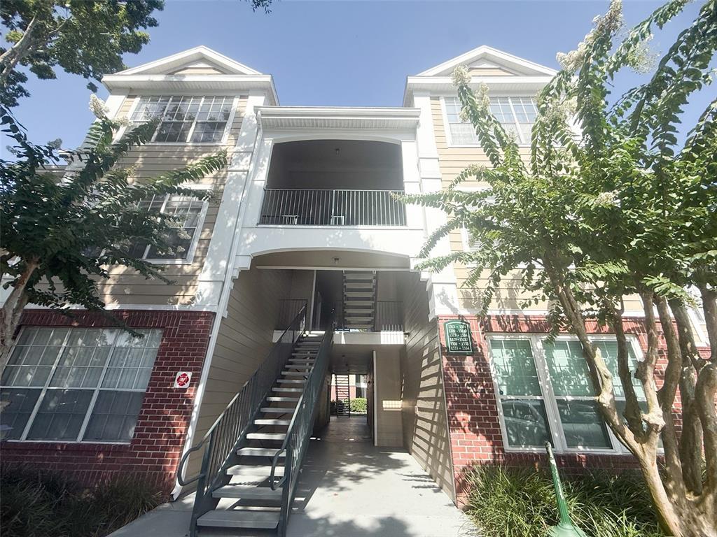 An exterior view of a multi-story apartment building with a central staircase and balconies — 13003 PLANTATION PARK CIRCLE UNIT 13110, ORLANDO, FL