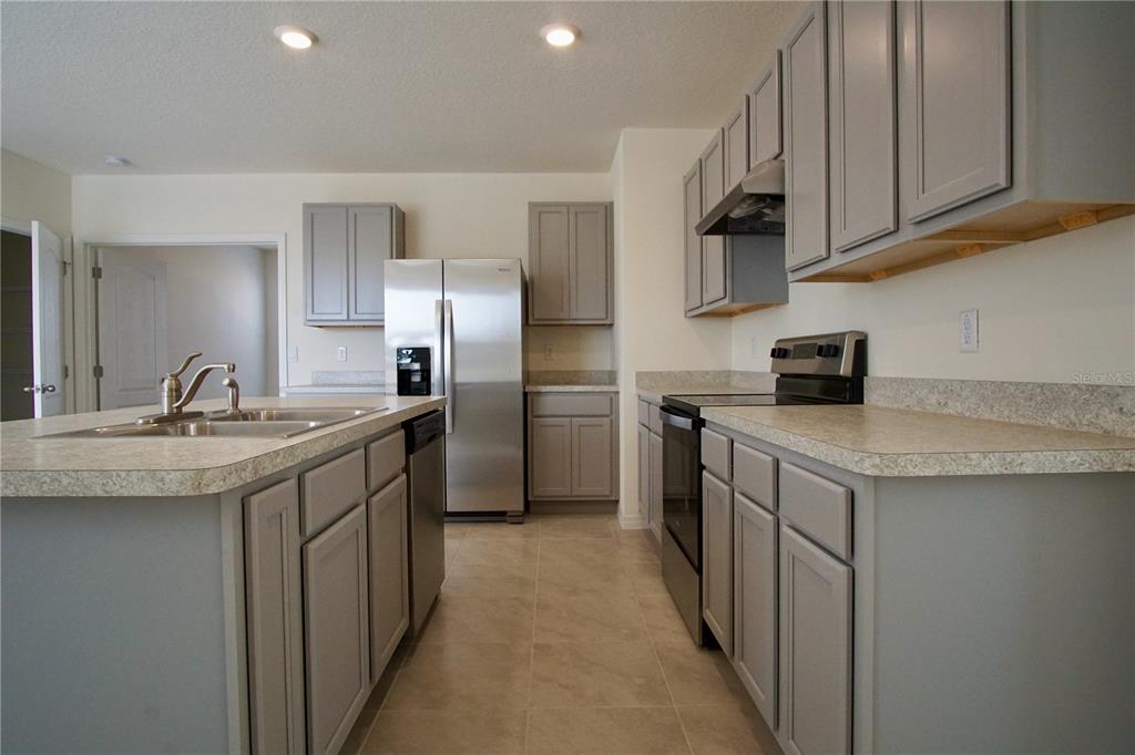 A kitchen features gray cabinets, stainless steel appliances, and light-colored laminate countertops — 1703 POST OAK DRIVE, DAVENPORT, FL
